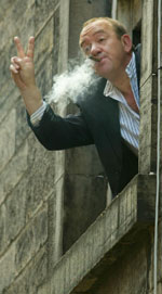 Mel Smith leaning out of the window of the Edingurgh Assembly Rooms Smoking a cigar